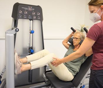 Bewegungstherapeutin leitet Frau an einem Muskeltrainingsgerät an