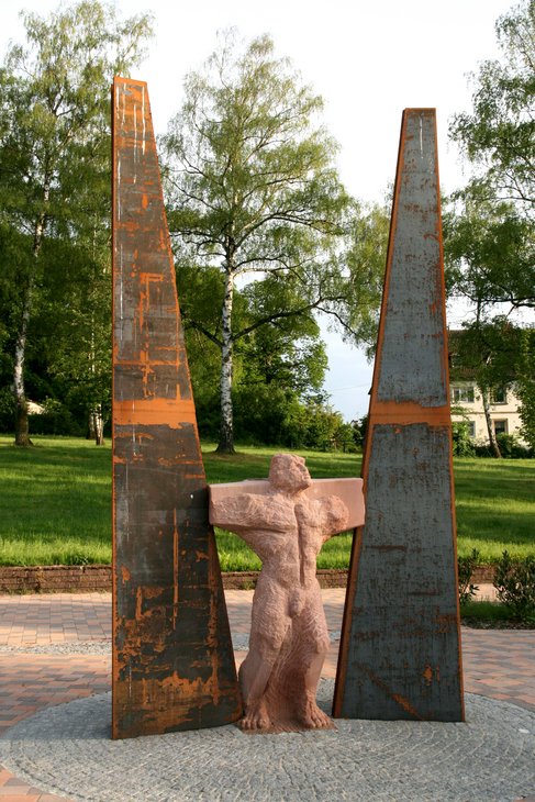 Die Gedenkstätte des Pfalzklinikums: eine Steinfigur ist eingeklemmt zwischen zwei Metallstücke.