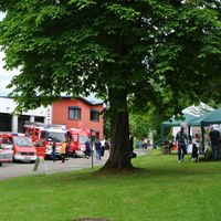 Man sieht eine Wiese mit Ständen und Menschen, dahinter Feuerwehrautos